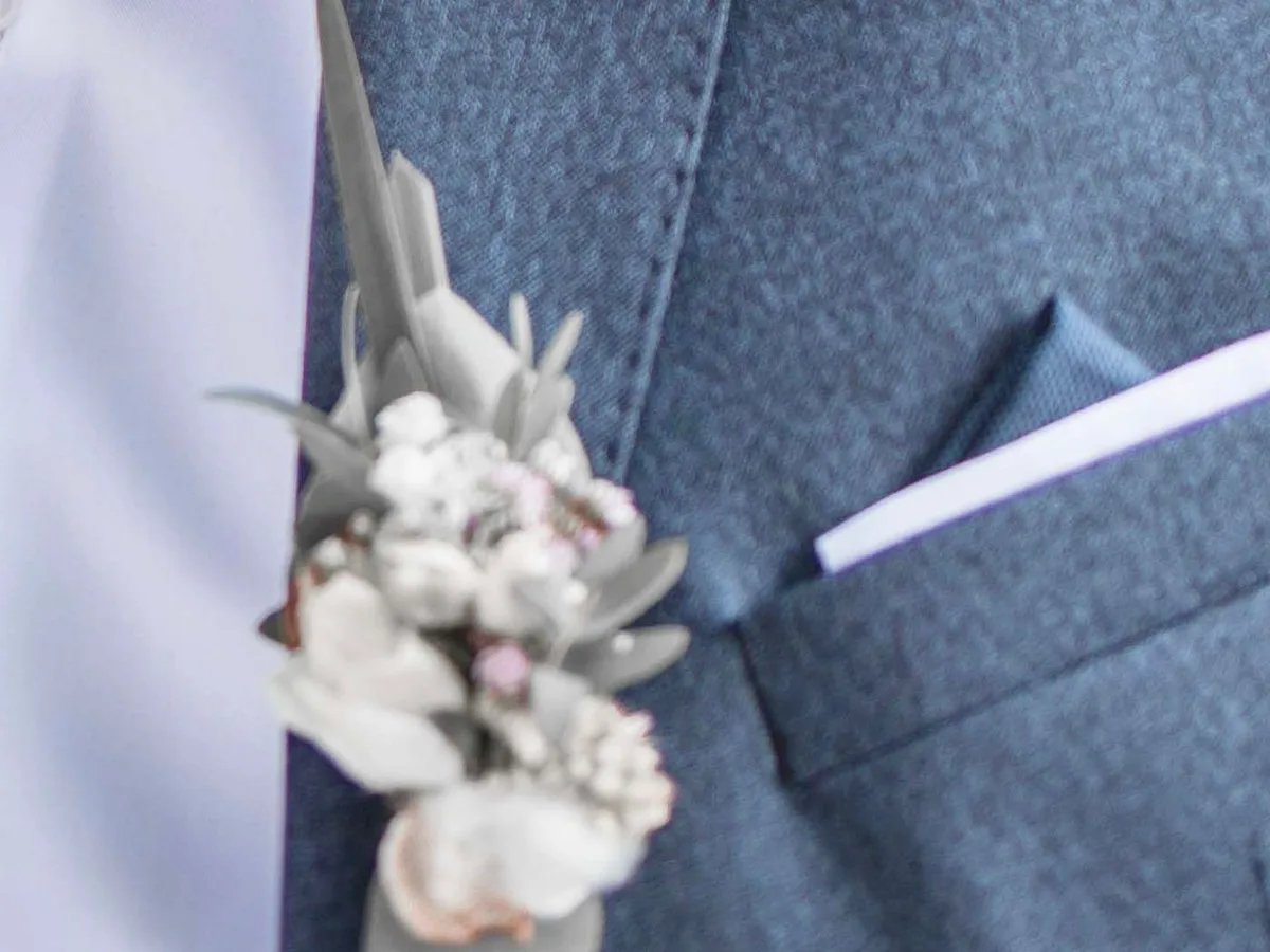 Ansteckblume am Revers des blauen Sakkos, daneben das Einstecktuch